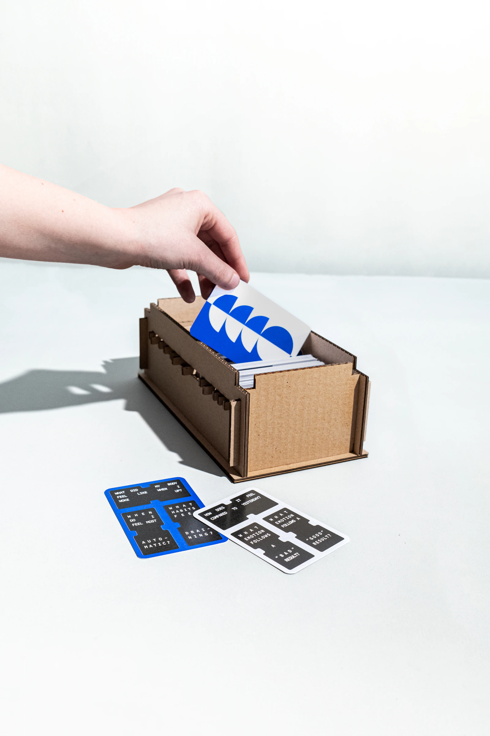 Hand placing a RE:MIND card into a wooden card box