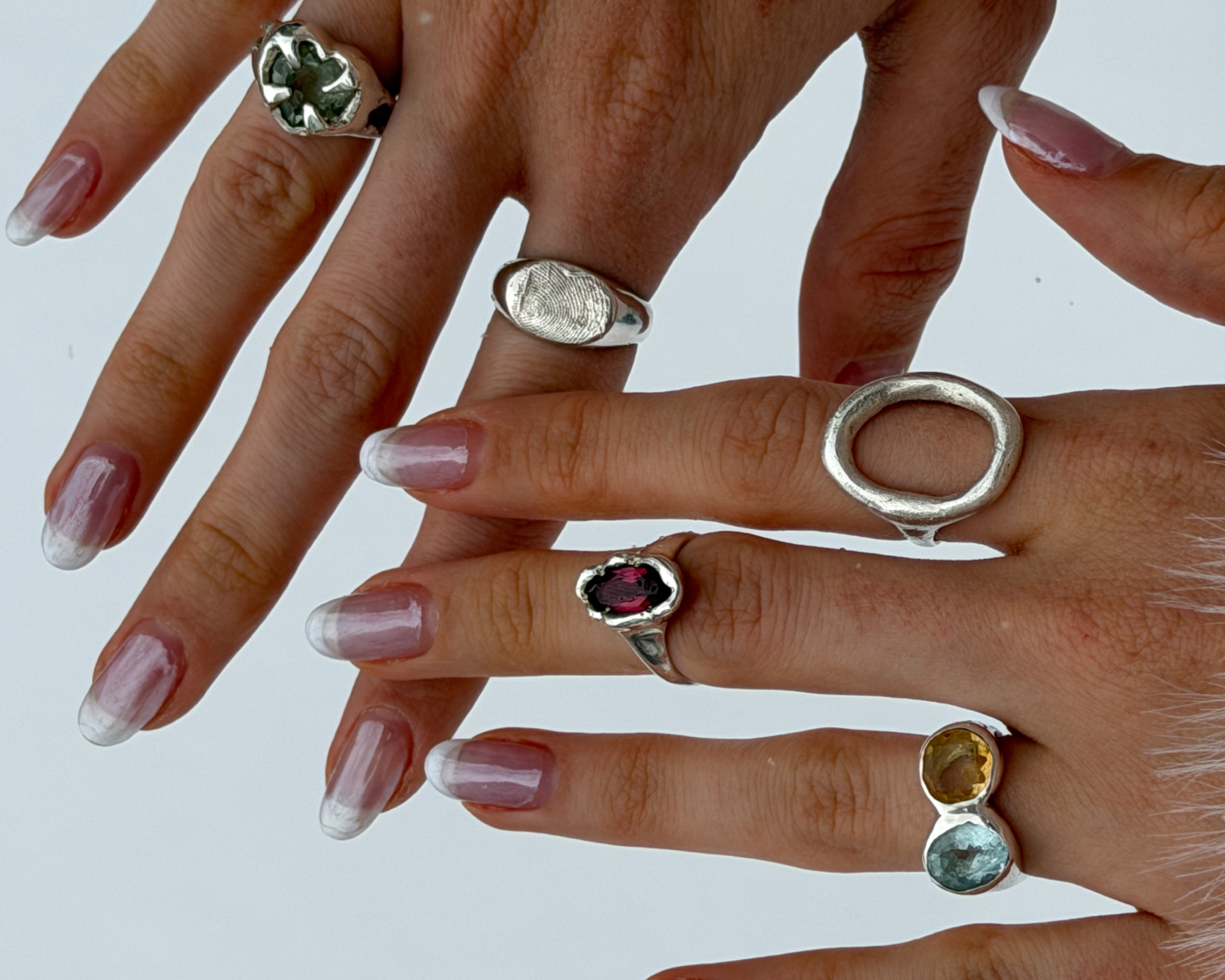 Two hands wearing an assortment of Maier Jewelry silver rings